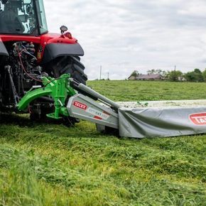 Zielona kosiarka dyskowa tylna typ OPTI CUT 280 firmy TALEX podczas koszenia łąki