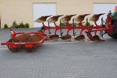 Używany Pług Vogel&Noot S 950 + wał Campbella Packer-220, rocznik 2004 na tle budynku gospodarczego 
