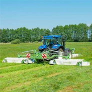 Niebieski traktor rolniczy z zestawem kosiarek MegaCUT firmy Samasz podczas koszenia trawy na łące