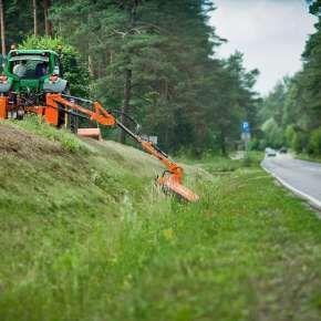 Zielony ciągnik rolniczy na skarpie kosi trawę za pomocą ramienia wysięgnikowego KWT firmy Samasz www.korbanek.pl