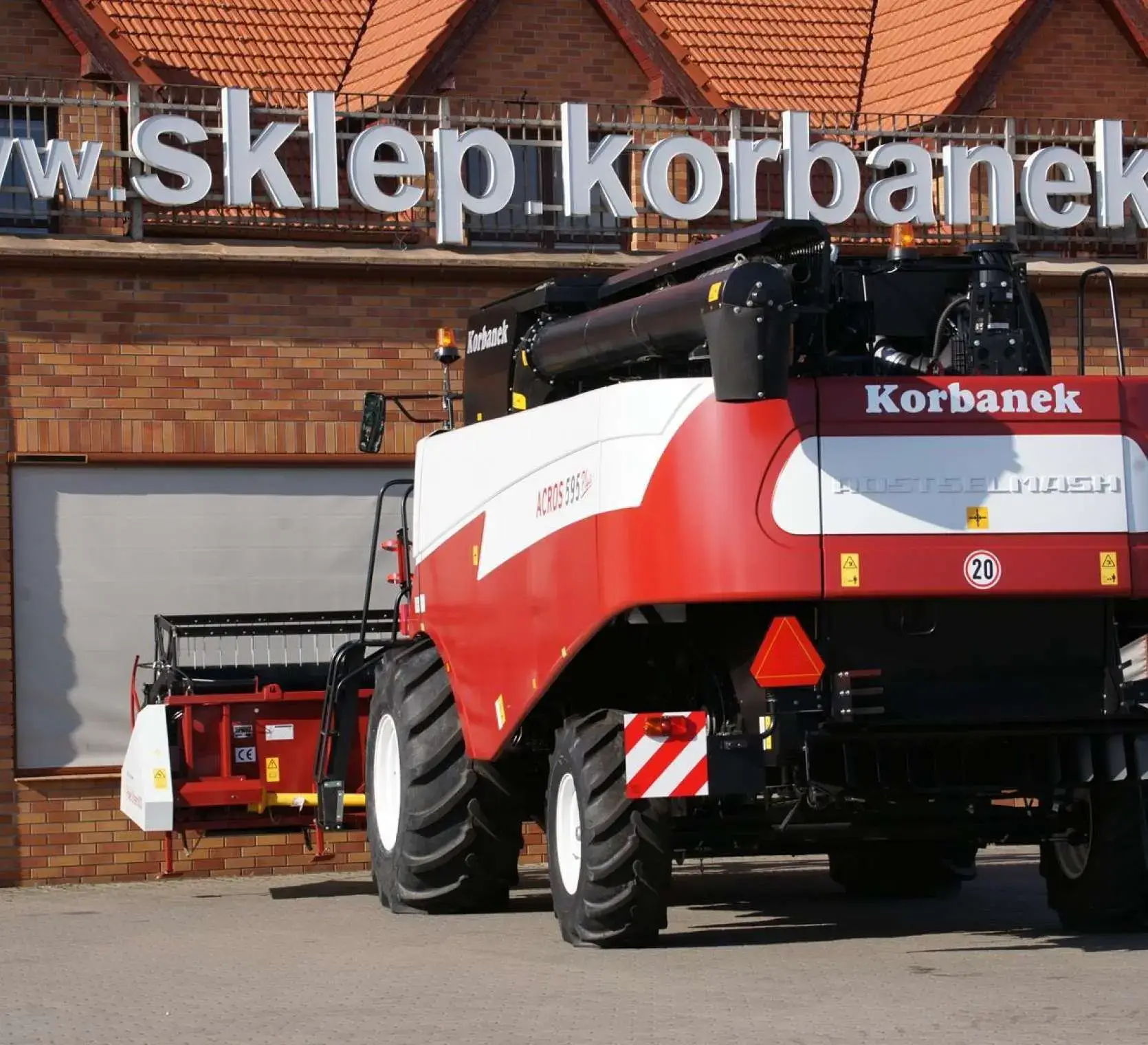 Zdjęcie przedstawiające kombajn Rostselmash Acros 595 + na tle sklepu części Korbanek. Widok z tyłu kombajnu Acros 595 + od Korbanek.