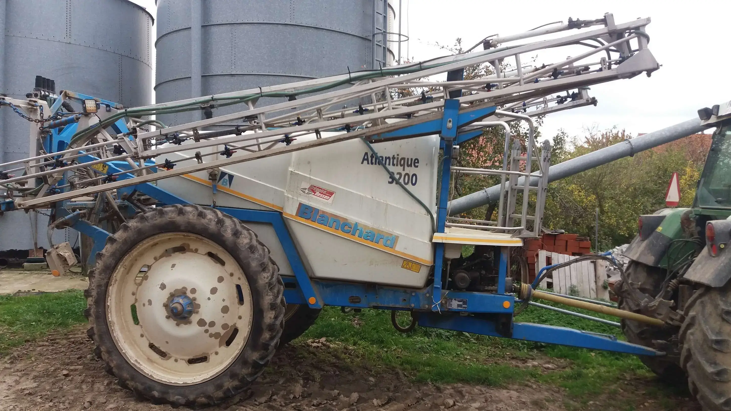 OPRYSKIWACZ BLANCHARD 3200/20 używany zdjęcie n tle silosów Używany OPRYSKIWACZ BLANCHARD 3200/20, 2007r