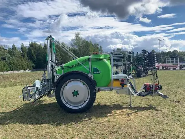Opryskiwacz zaczepiany o pojemności 1500 litrów i o belce polowej 15 metrów na zdjęciu jest widoczny z boku prawa strona widok na koło i dyszel zaczepowy Opryskiwacz zaczepiany Tolmet Bruno stosowany do ochrony roślin