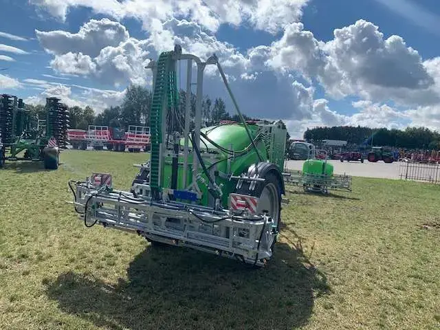 Opryskiwacz widoczny na tle placu maszyn Korbanek widok na złożona belke polową Opryskiwacz zaczepiany Tolmet Bruno stosowany do ochrony roślin zaczepiany polowy belka 15 metrów
