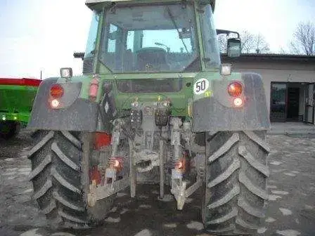 Tył używanego ciągnika rolniczego Fendt 412 Vario na drugim planie rozsiewacz nawozów Amazone  
