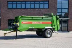 przed fabryką stoi rozrzutnik Bergmann jednoosiowy. 