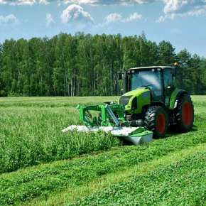 Na zielonym ciągniku firmy CLAAS zamontowana jest zielona kosiarka czołowa dyskowa KDF 300 firmy Samasz która kosi koniczynę z trawą na łące.