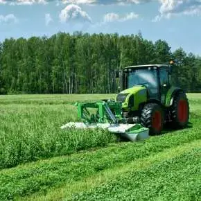 Na zielonym ciągniku firmy CLAAS zamontowana jest zielona kosiarka czołowa dyskowa KDF 300 firmy Samasz która kosi koniczynę z trawą na łące.