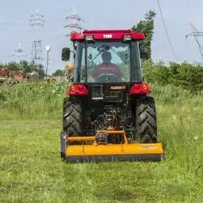 Pomarańczowa kosiarka mulczująca PIKO 130 firmy Samasz podczepiona do czerwonego traktora mulczuje nieużytek www.korbanek.pl