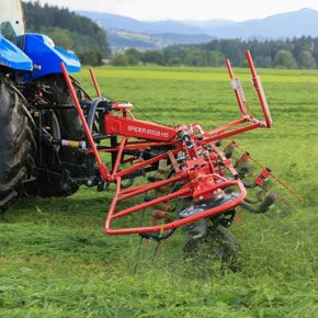 Czerwony przetrząsacz 8-wirnikowy SPIDER 815/8 firmy SIP podczas pracy z niebieskim ciągnikiem