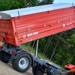 Czerwona przyczepa rolnicza wywrotka model T711/3 firmy Metal-Fach wyposażona w plandekę i dodatkowe burty