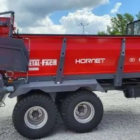 Czerwona rozrzutnik obornika tandem model N267/1 firmy Metal-Fach wyposażony w deflektory mechaniczne