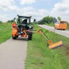 Widok ciągnika rolniczego koszącego pobocze za pomocą kosiarki wysięgnikowej KOLIBER 400 www.korbanek.pl