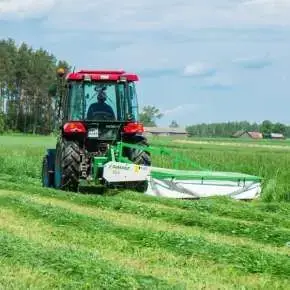 Czerwony traktor rolniczy z kosiarka rotacyjną bębnową firmy Samasz kosi trawę na pastwisku www.korbanek.pl