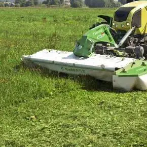Widok od przodu traktora rolniczego Claas z zawieszoną kosiarką przednią dyskową XT-F  firmy SaMASZ