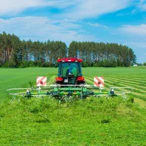 Czerwony traktor rolniczy przetrząsa skoszoną trawę za pomocą przetrząsacza zawieszanego P4-471 firmy Samasz www.korbanek.pl