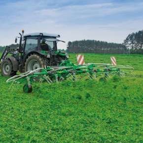 Zielony ciągnik Deutz-Fachr z ładowaczem i podczepionym przetrząsaczem karuzelowym P6-771 firmy Samasz przetrząsa koniczynę www.korbanek.pl