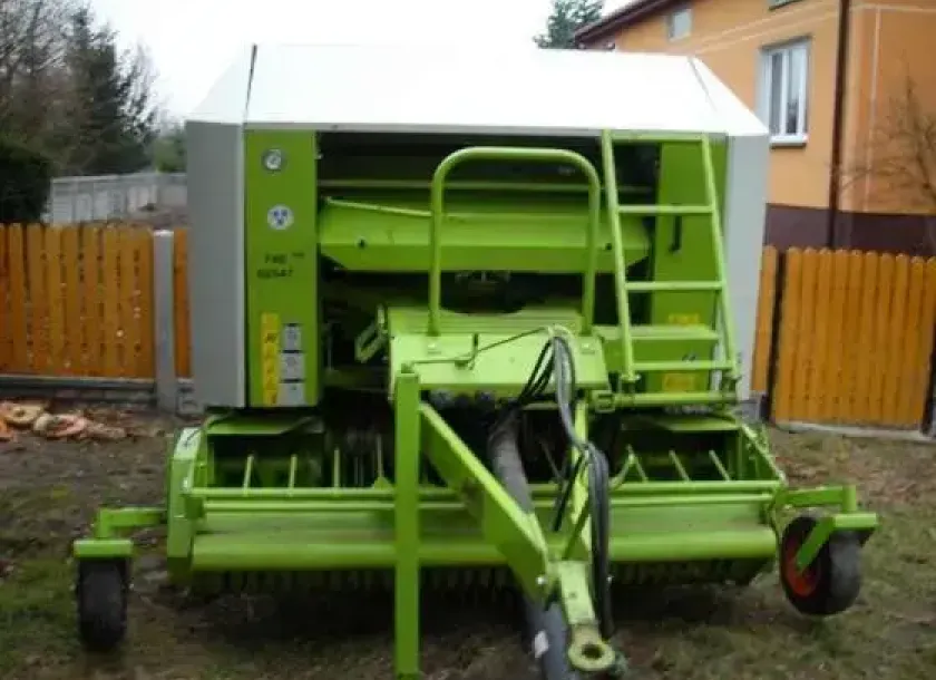 Claas Rolant 255 RC używana prasa widok z przodu w tle budynek 