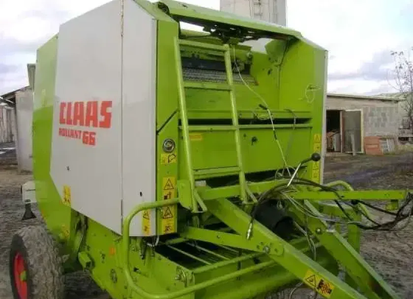 Prasa zwijająca używana marki Claas Rollant 66 w tle budynek gospodarczy