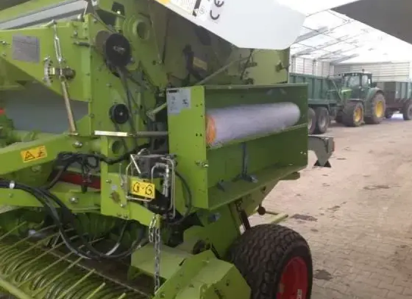 Prasa Claas Variant 260  z 2005 w hali w tle traktor z przyczepą