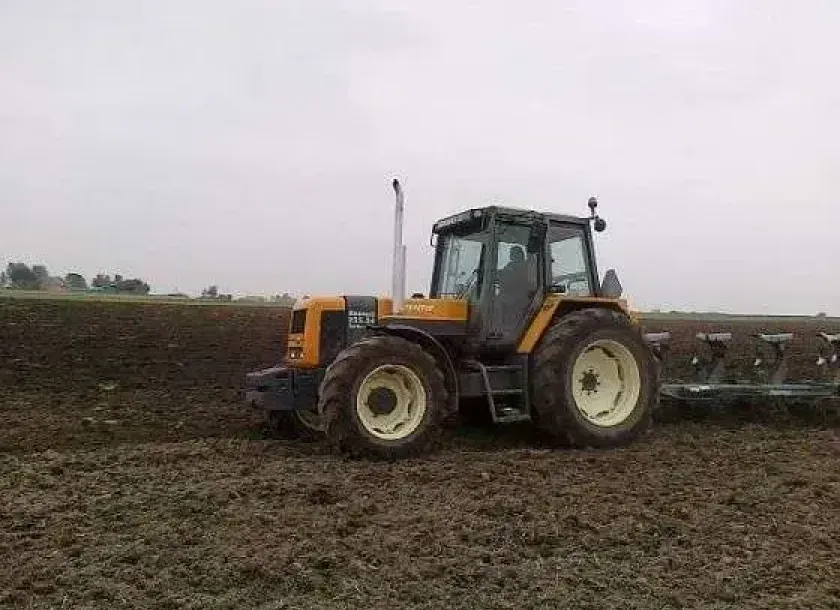 Używany ciągnik rolniczy Renault 155.54 z zamontowanym pługiem podczas orki 