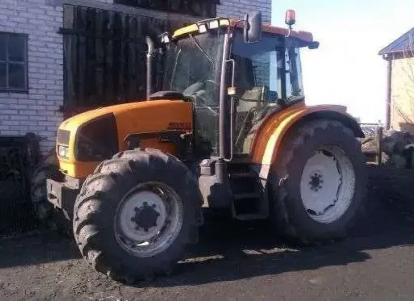 Używany żółty traktor rolniczy Renault Ares 550 RX w zabudowaniach gospodarstwa 