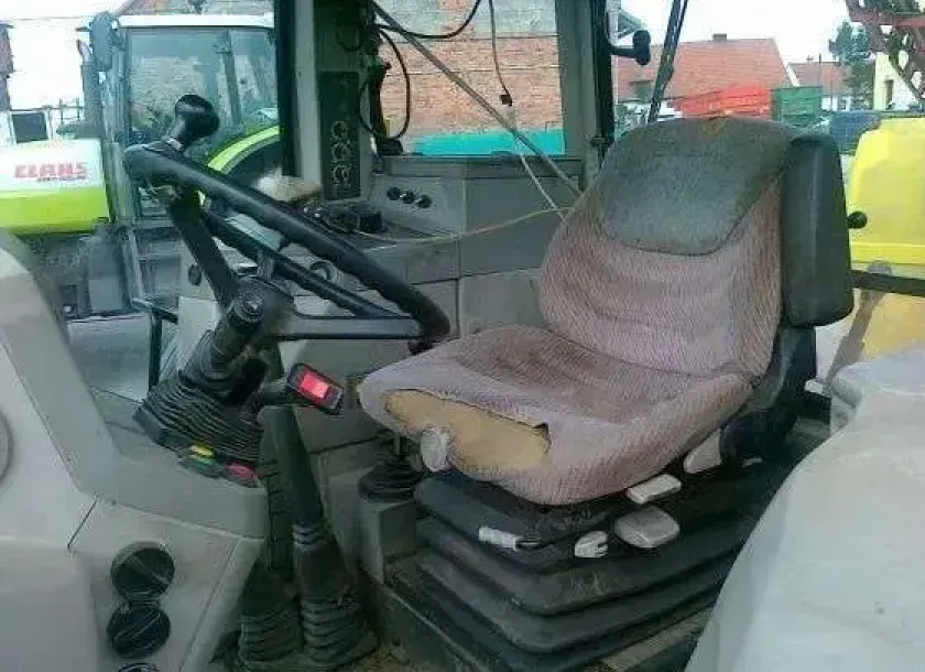 Wnętrze kabiny używanego ciągnika Fednr 309 widok na kierownicę i siedenie operatora w tle ciągnik marki Claas 