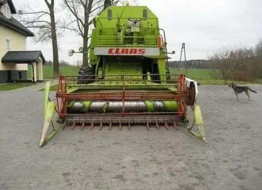 Używany Kombajn zbożowy Claas Mercator 75 z hederem  na utwardzonym placu widok z przodu