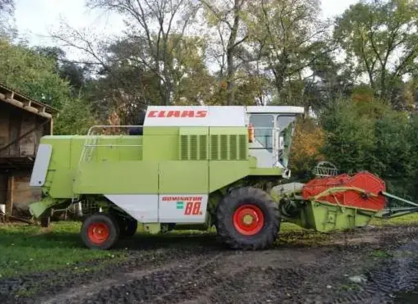Używany Kombajn zbożowy Claas Dominator 88s widok z prawej strony na tle wysokich drzew