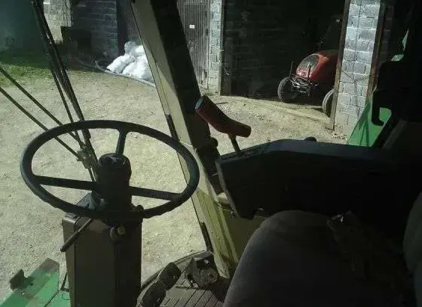 Zdjęcie przedstawiające wnętrze kabiny kombajnu używanego John Deere 2056. 