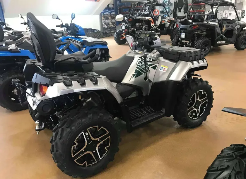 Srebrny metalik Quad Polaris Sportsman 1000 Touring na tle innych modeli pojazdów Polaris