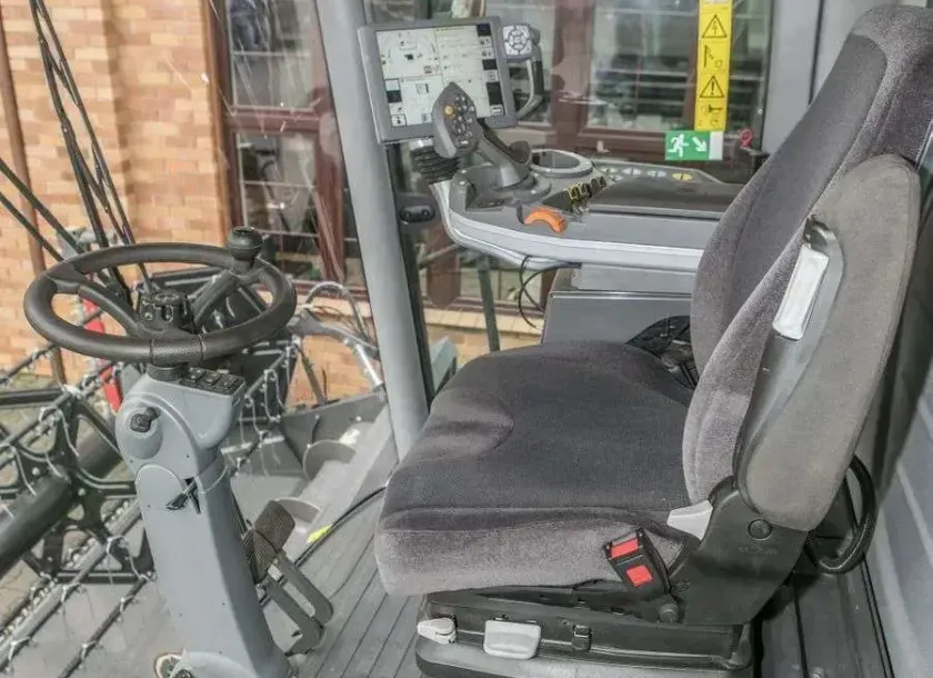 Wnętrze kabiny używanego kombajnu Fendt 6335 widok na kierownice i siedzenie operatora  