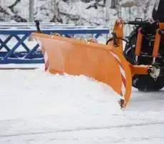 Pomarańczowy czołowy pług spychacz do śniegu Smart firmy samasz odśnieża chodnik Korbanek.pl