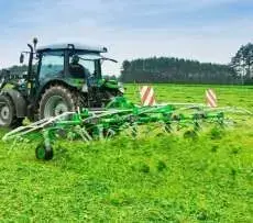 Zielony przetrząsacz zawieszany Samasz model P6 podczas pracy - przetrząsa trawę