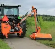 Pomarańczowa kosiarka komunalna Koliber firmy Samasz kosi trawę na poboczu drogi Korbanek.pl