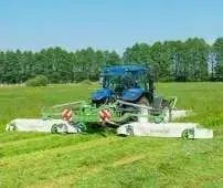 Niebieski traktor rolniczy z zestawem kosiarek MegaCUT firmy Samasz podczas koszenia trawy na łące