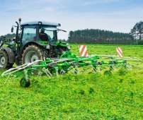 Zielony przetrząsacz zawieszany Samasz model P6 podczas pracy - przetrząsa trawę