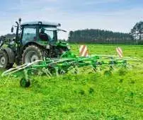 Zielony przetrząsacz zawieszany Samasz model P6 podczas pracy - przetrząsa trawę