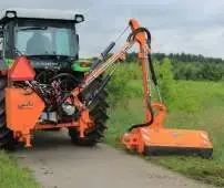Pomarańczowa kosiarka komunalna Koliber firmy Samasz kosi trawę na poboczu drogi Korbanek.pl