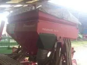 Pod wiatą stoi używany siewnik pneumatyczny Marki ACORD PNEUMATIC DA-S 4,5 metra szerokości roboczej