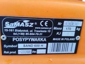 Pomarańczowa tabliczka znamionowa na czarnej posypywarce piasku i soli Samasz Sand 400