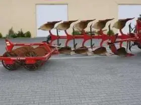 Używany Pług Vogel&Noot S 950 + wał Campbella Packer-220, rocznik 2004 na tle budynku gospodarczego 