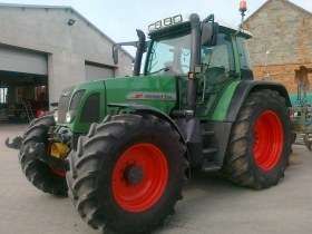 Zielony ciągnik niemieckiego producenta Fendt 714 Vario w zabudowaniach gospodarstwa 