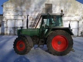 Używany ciagnik rolniczy Fendt 310 na tle zabudowań gospodrstwa widom na lewy bok pojazdu 