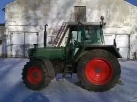 Używany ciagnik rolniczy Fendt 310 na tle zabudowań gospodrstwa widom na lewy bok pojazdu 