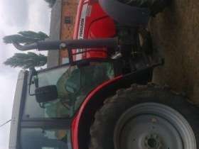 Ujęcie z boku na ciągnik rolniczy marki Massey Ferguson 5465 na tle gospodarstwa, kabina, koła, korbanek.pl