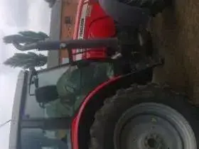 Ujęcie z boku na ciągnik rolniczy marki Massey Ferguson 5465 na tle gospodarstwa, kabina, koła, korbanek.pl