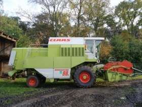 Używany Kombajn zbożowy Claas Dominator 88s widok z prawej strony na tle wysokich drzew