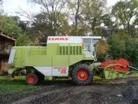 Używany Kombajn zbożowy Claas Dominator 88s widok z prawej strony na tle wysokich drzew