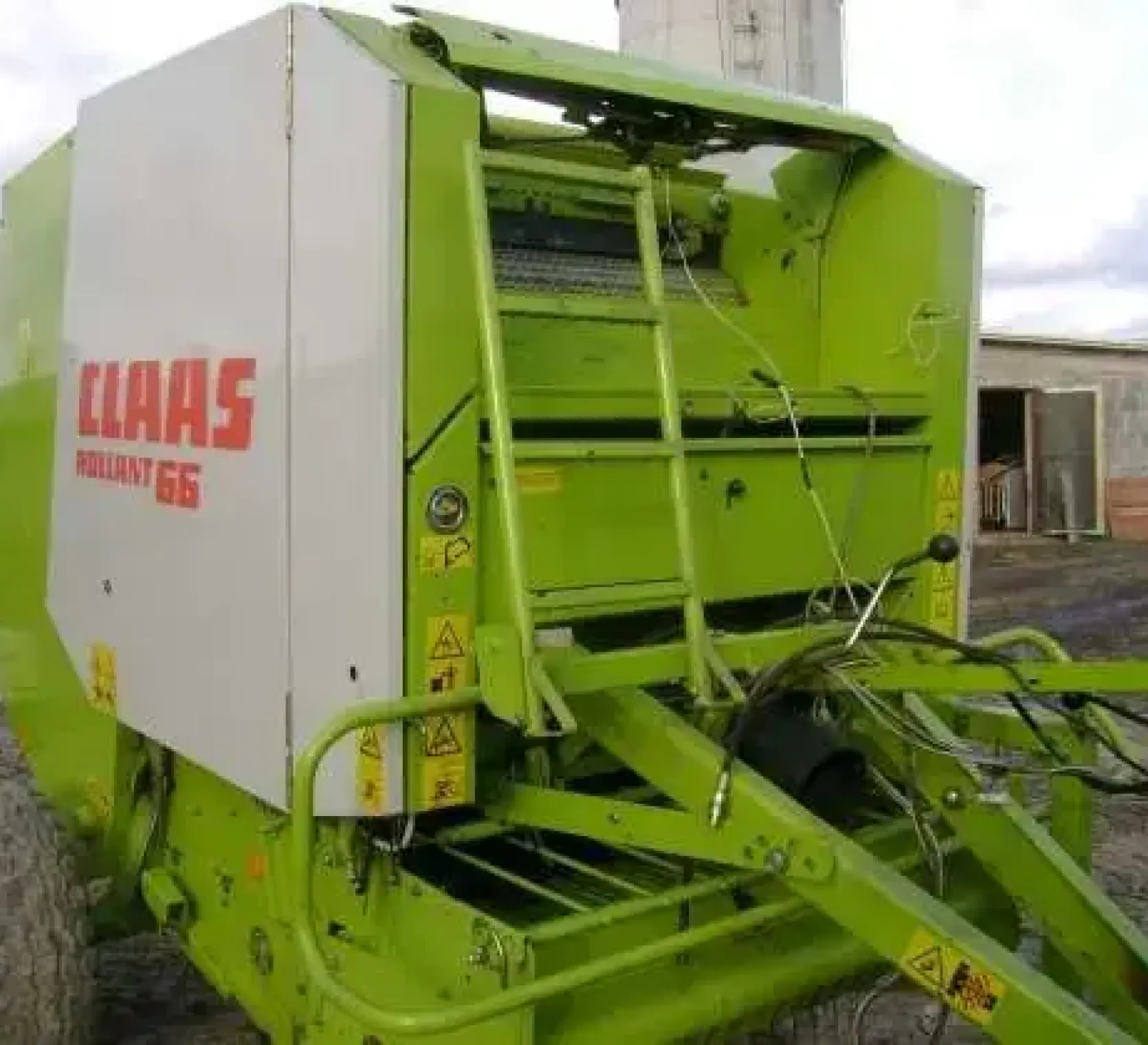 Prasa zwijająca używana marki Claas Rollant 66 w tle budynek gospodarczy